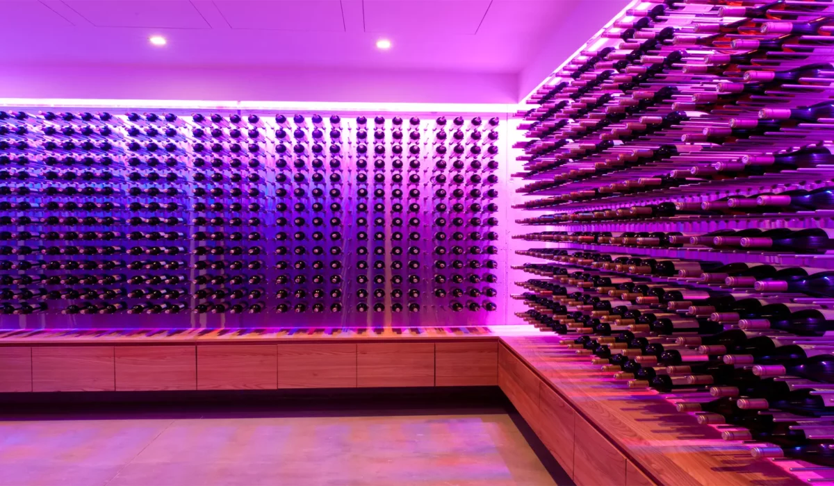 Ściana winnicy z zawieszonymi na niej setkami butelek skąpana w fioletowym świetle